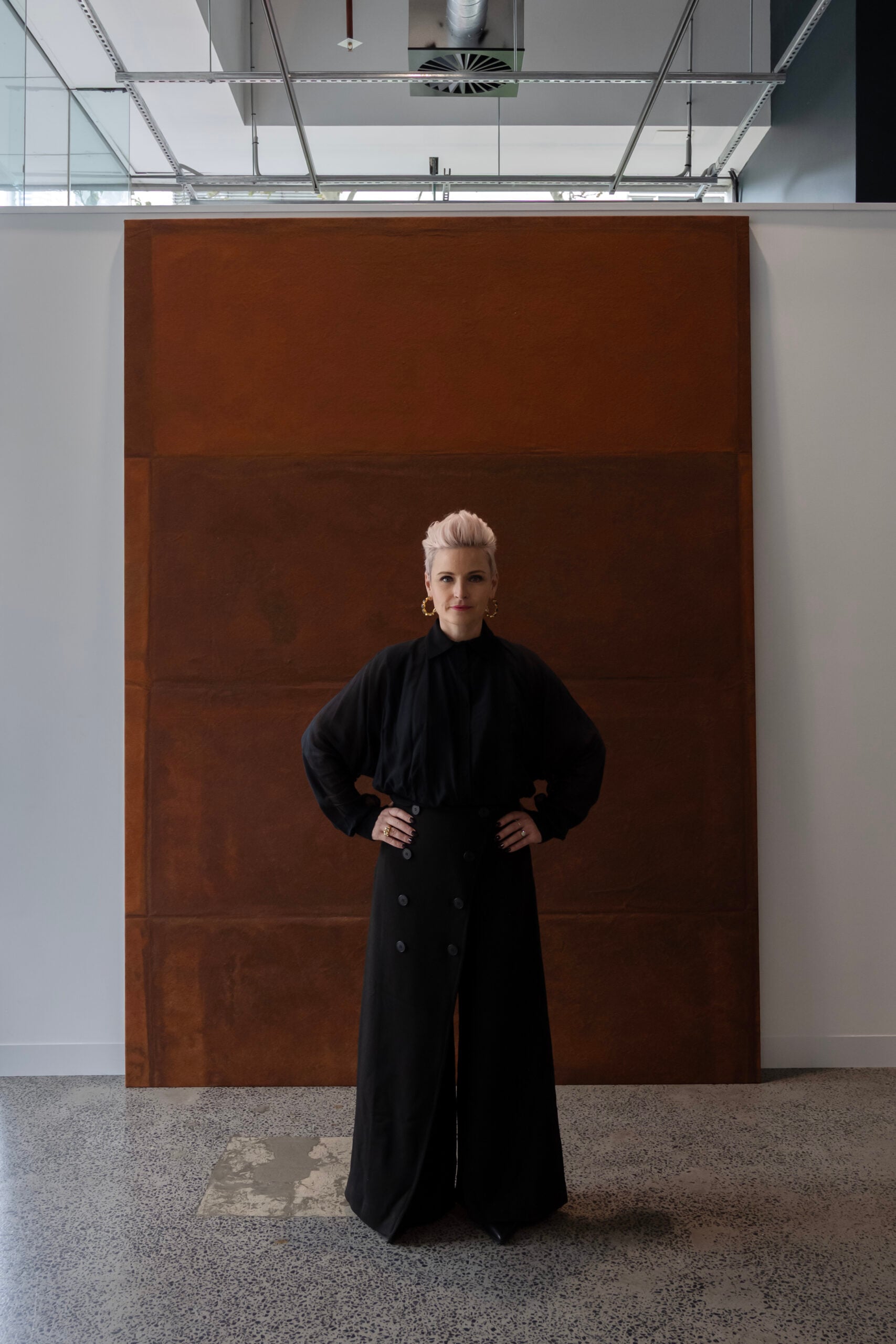 Gallery Director, Sophie Vander, standing inside the gallery in front on a large orange Andre de Vanny painting.