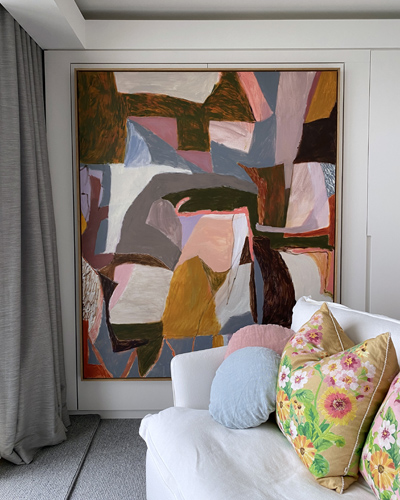 Diana Miller painting in front of a sofa with floral cushions